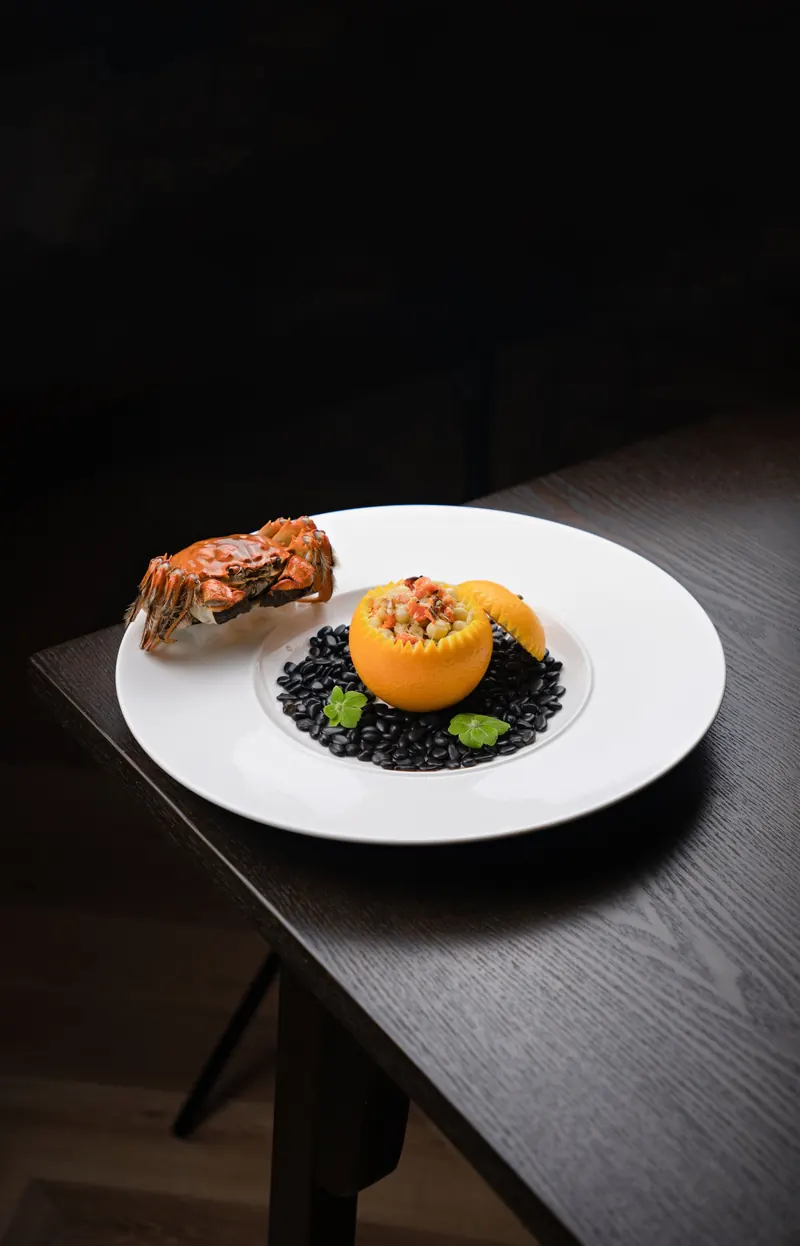 Cangrejo con naranja sobre frijol negro en plato blanco