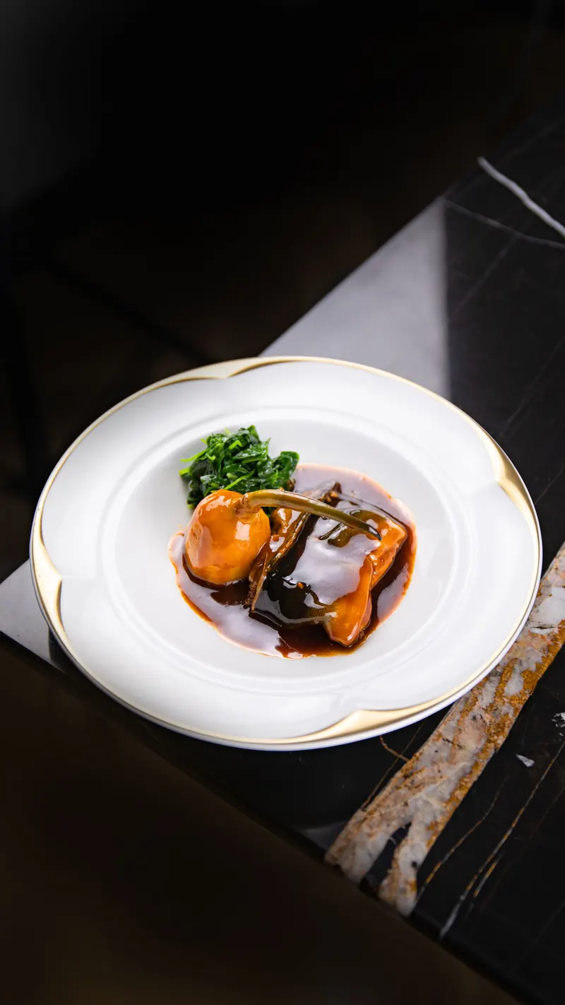 Setas glaseadas con salsa oscura y espinaca en plato de borde dorado